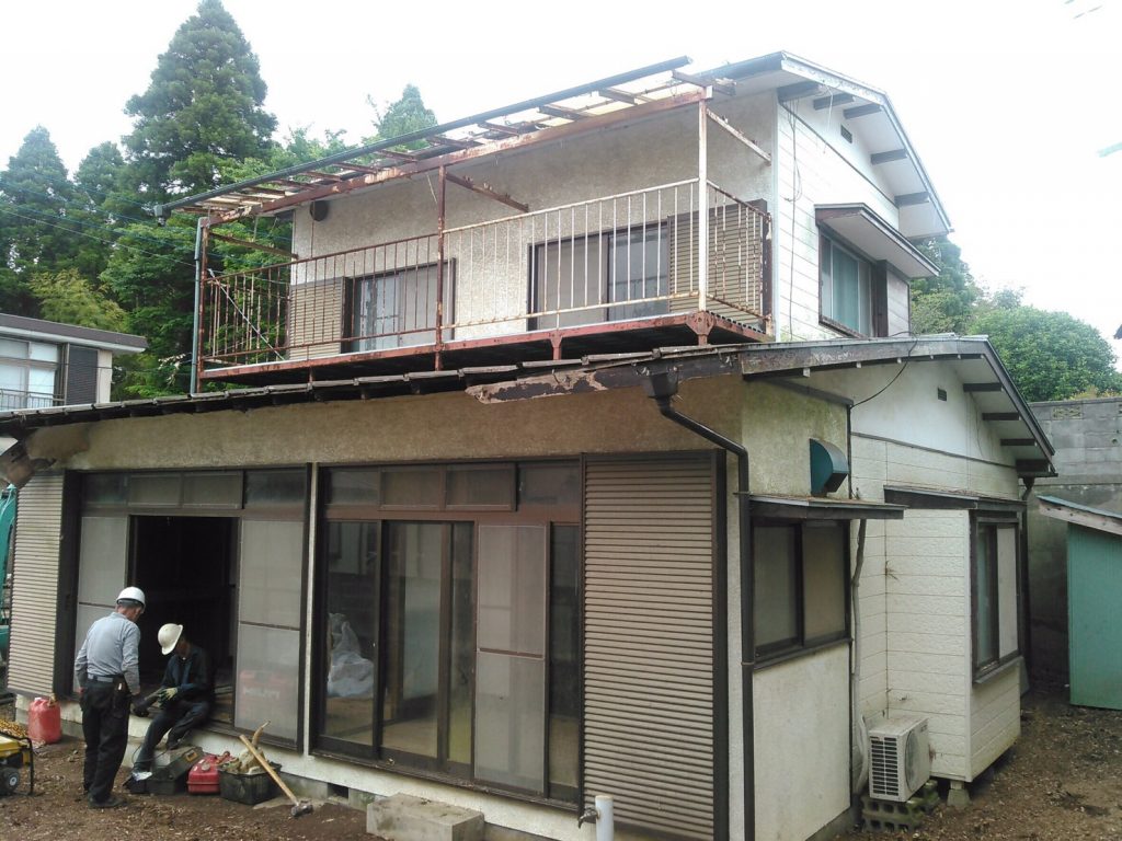 足場が組まれ、庭が手入れされている古い住宅