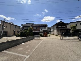 青空の下、住宅が並ぶ静かな住宅街の道路