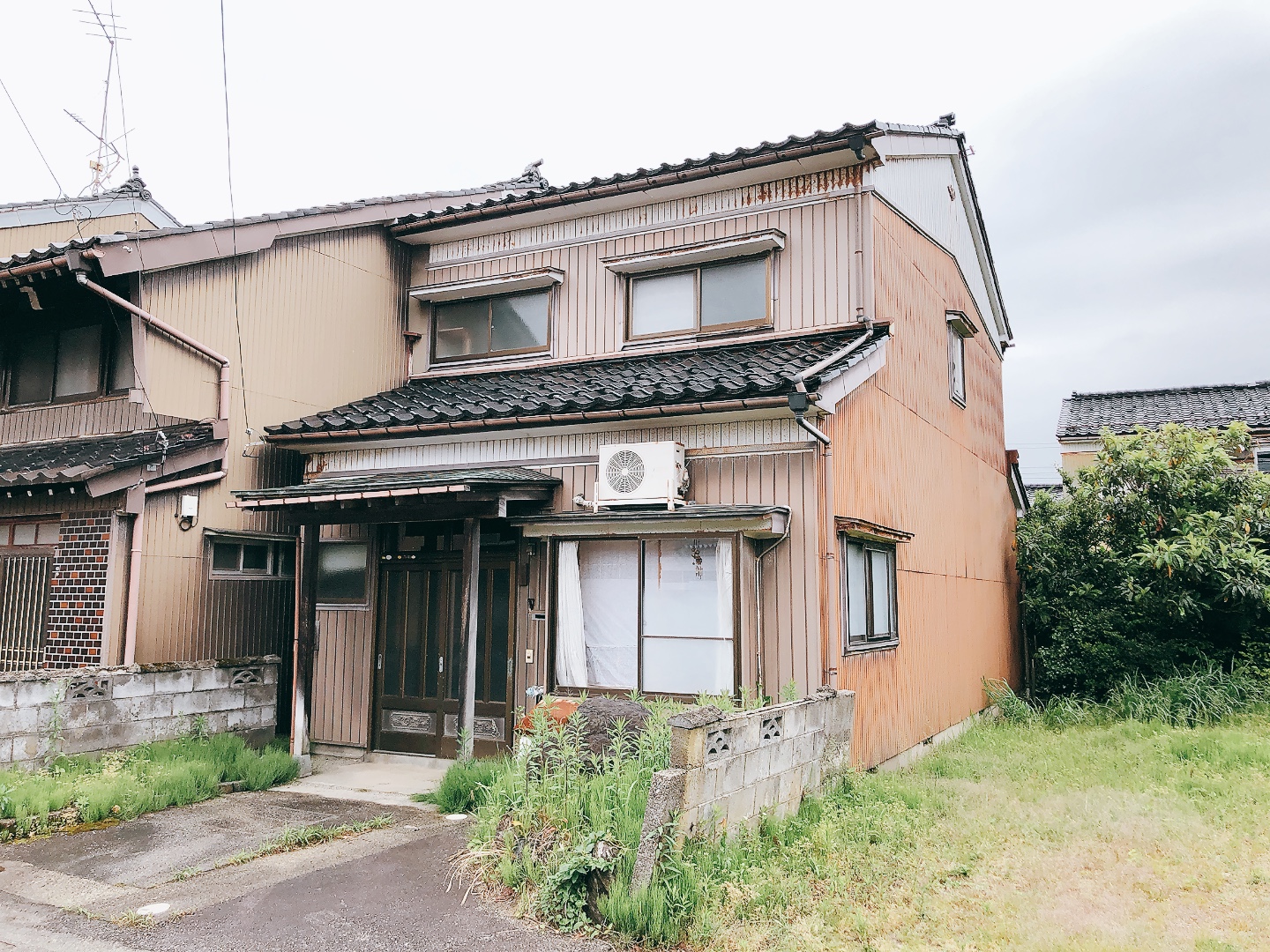 庭に雑草が生えた築古の戸建の外観