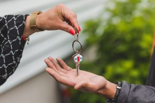 家の形のキーホルダーがついた鍵を渡す手元